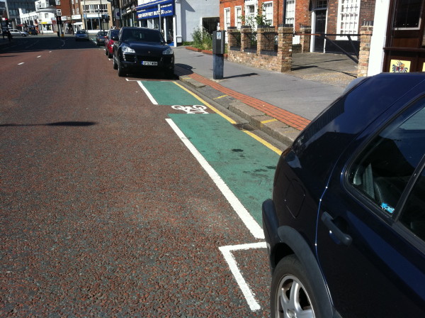 very short green cycle lane between two parking spaces