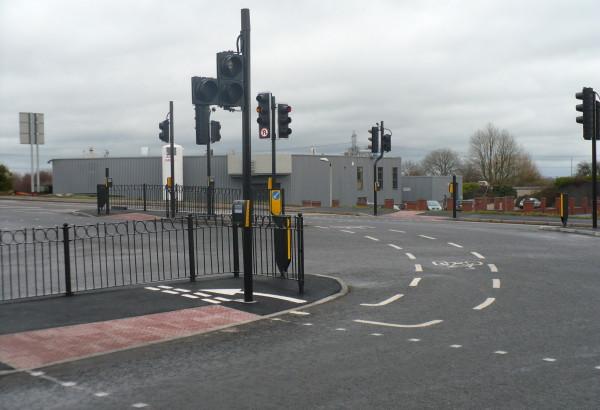 a cycle lane directs cyclists to negotiate a sharp turn and squeeze between the light pole and the railings before giving way to the foot traffic