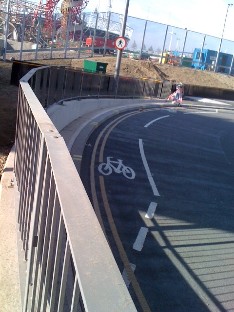 short cycle lane squeezed between the edge of a roundabout and a fence