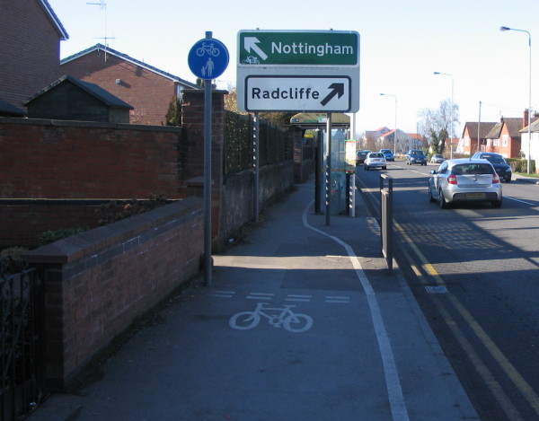 narrow cycle path gets even thinner to squeeze past a front gate and through a bus shelter